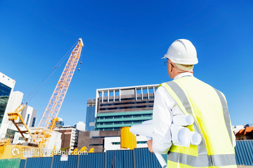 建筑工地的工程师建设者工程师建筑工人施工场景穿着带蓝图的安全背心